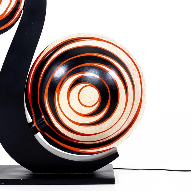 Large table lamp with black s-shaped base and plastic lens-shaped lampshades with snail pattern in red, black and beige....