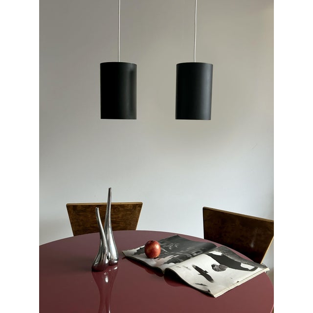 When lit, a soft warm glow spills from the open base of each shade — the quiet payoff of the Louis Poulsen cylinder...