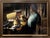 In "Late Supper," a woman stands in a warmly lit kitchen, her focused expression revealing a moment of quiet contemplation...