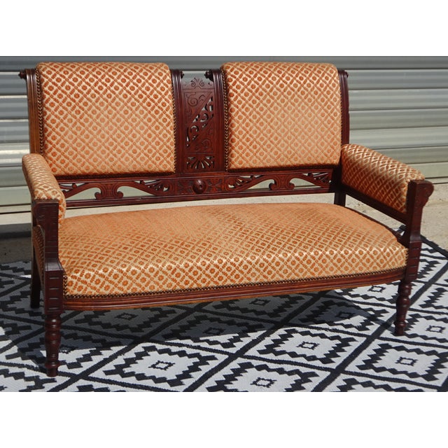 Two-seater bench in wood and fabric. Solid beech frame with numerous carved relief motifs on the legs and in the center of...