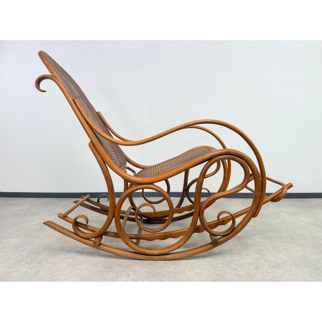 Large Thonet rocking chair no.7021B in excellent structural condition. The rattan cane is mostly tight and intact, with...