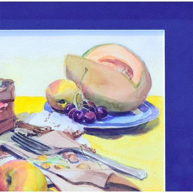 Original vintage watercolor painting featuring delectable cake and fruit on a table spread with a yellow tablecloth....