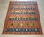 Vintage Persian kilim, circa 1970s, handwoven in a graphic flatweave design. The rug features a warm terracotta-red ground...