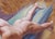 This oil on panel artwork depicts a nude figure reclining on a surface, captured from a bird's-eye view. The warm,...
