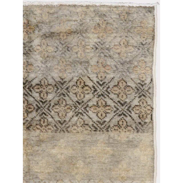 This mid-20th-century Turkish Anatolian rug presents a restrained composition of patterned end panels surrounding a broad,...