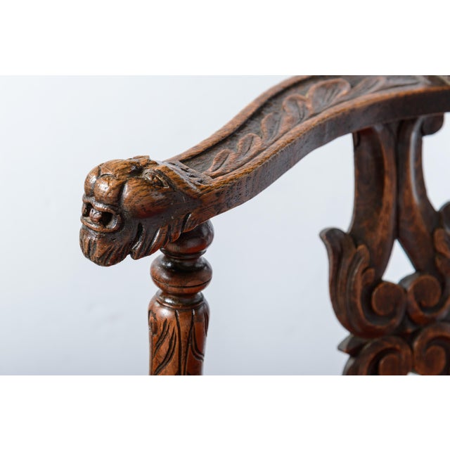 Heavily carved, red fabric upholstered corner chair. C.1860. Ball and claw leg in the front, caved open splats and lion...