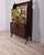 Tall lacquered wood sideboard, lower section with one door and three drawers, upper section with a decorated panel, drop-...