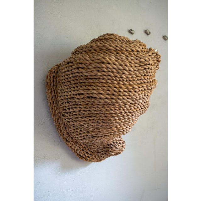 A large handmade shell sculpture built up from coiled natural rope — row on row of twisted cord worked over a woven...