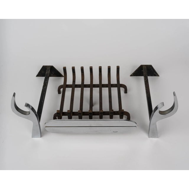 This unique, modern stainless steel fireplace set includes a pair of flame-shaped signed andirons and a signed log rack....