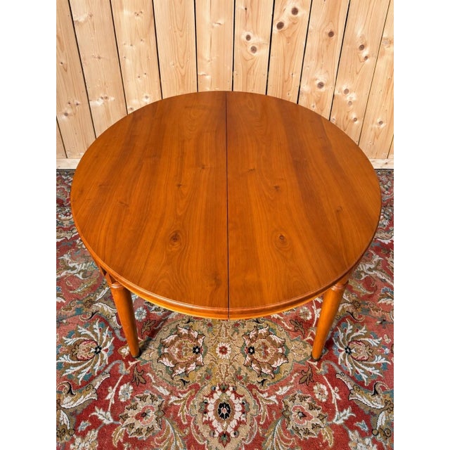 Louis XVI style cherrywood table comprising a 115 cm diameter tabletop and a 58 cm extension leaf. Six legs ending in...
