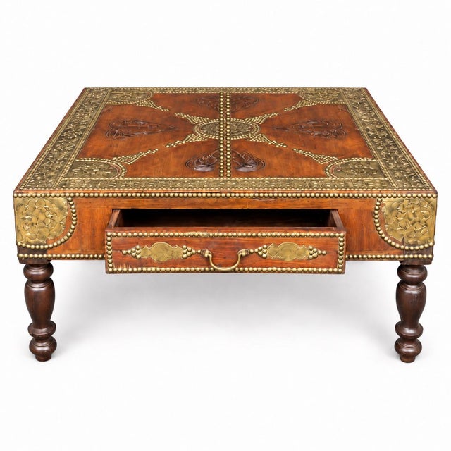 This is a mid-century Anglo-Indian style carved teak and brass inlaid coffee table. It is known as a Pooja Chowki or low...