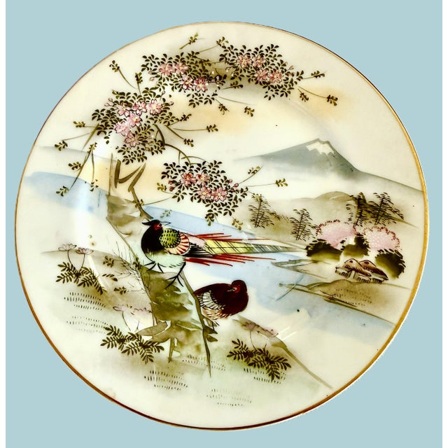 Hand‑painted Japanese Kutani plates, measuring 7.25” and featuring birds, cherry blossoms, and a serene mountain...