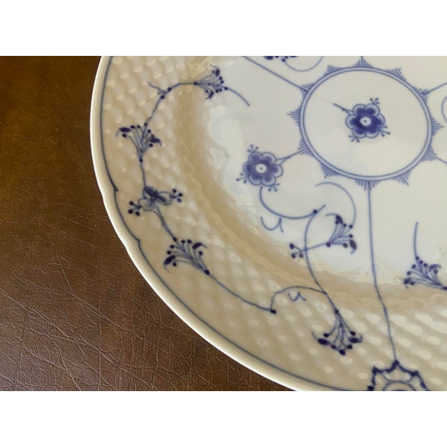 Hand painted delicate blue stylized floral motifs and fine lines radiating from the center; subtle ribbed texture