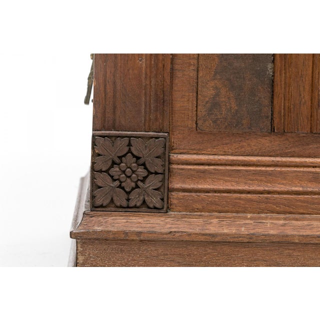 A vintage rectangular wooden chest with a sloped, molded lid, paneled sides with burled wood insets, carved floral rosette...