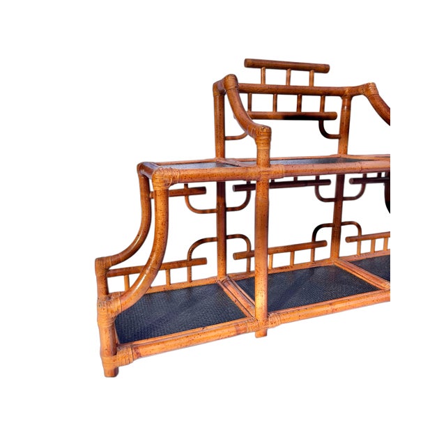 A vintage wall hanging shelf in burnt bamboo with black grasscloth lining, featuring extensive fretwork in a pagoda shape.