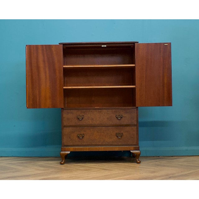 A quality Art Deco style burr walnut tallboy or housekeeper’s cupboard, circa 1950s There is a cupboard at the top and...