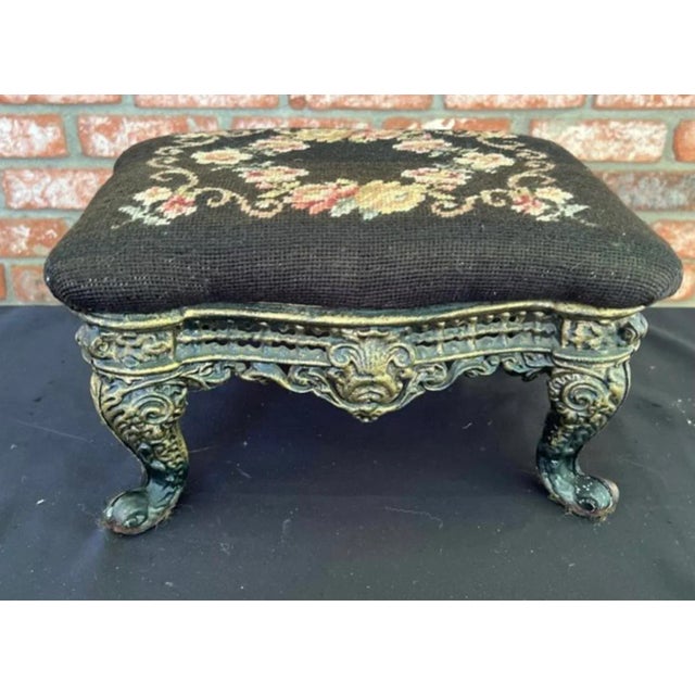 Antique cast iron ottoman with needlepoint upholstery. The ottoman is solid and carved. The fabric is original, wear...