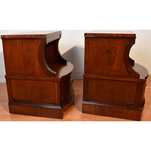 A matching pair of antique style wooden nightstands crafted in a rich, warm wood finish. Each piece features a rectangular...