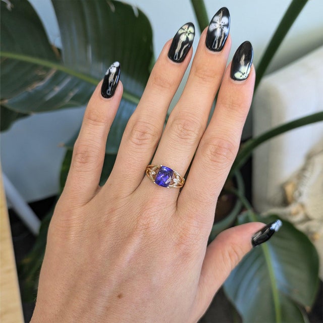 A 2.74-carat cushion tanzanite glows in a velvety blue at the heart of this solid 14K yellow gold ring, framed by ten lab...