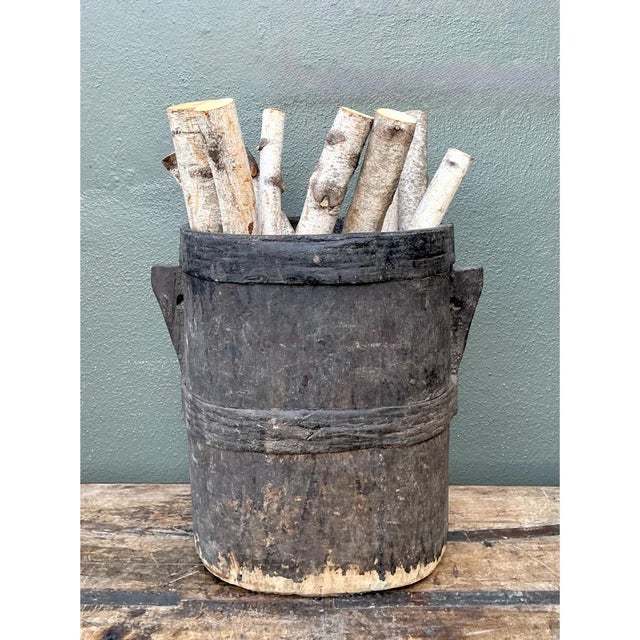 This vintage wood bucket is a striking example of hand-hewn utilitarian craft, carved from a single tapering cylindrical...