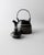 This vintage ceramic teapot from the 1980s features a striking black surface accented with fine white line detailing,...