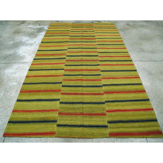 This Mid-20th century Turkish Flatweave Kilim rug, showcases a striking horizontal stripe design set against a vibrant...