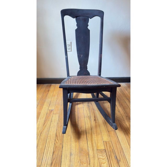 Vintage armless wooden rocking chair with woven cane seat, likely dating to the late 19th or early 20th century. The chair...
