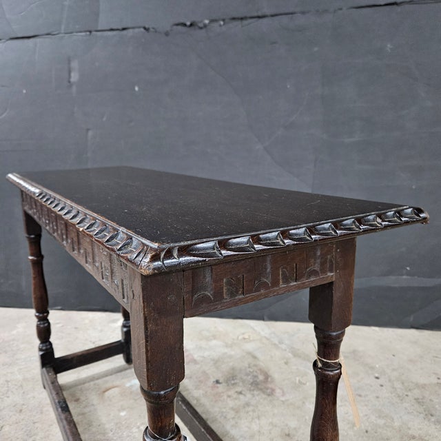 This English Oak Jacobean Revival Lamp/Sofa Table With Carved Apron and Turned Legs has a nice stretcher base. It is...