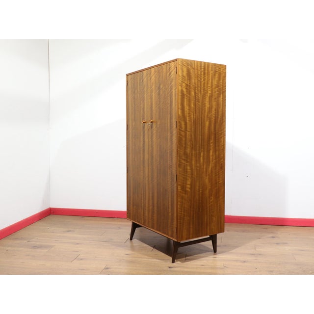 This stunning mid century walnut armoire by renowned British furniture maker Alfred Cox showcases beautiful wood grain and...