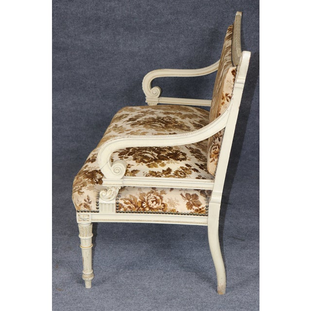 A wonderfully decorative and generously proportioned Louis XVI-style settee, distinguished by its heavily stylized carved...