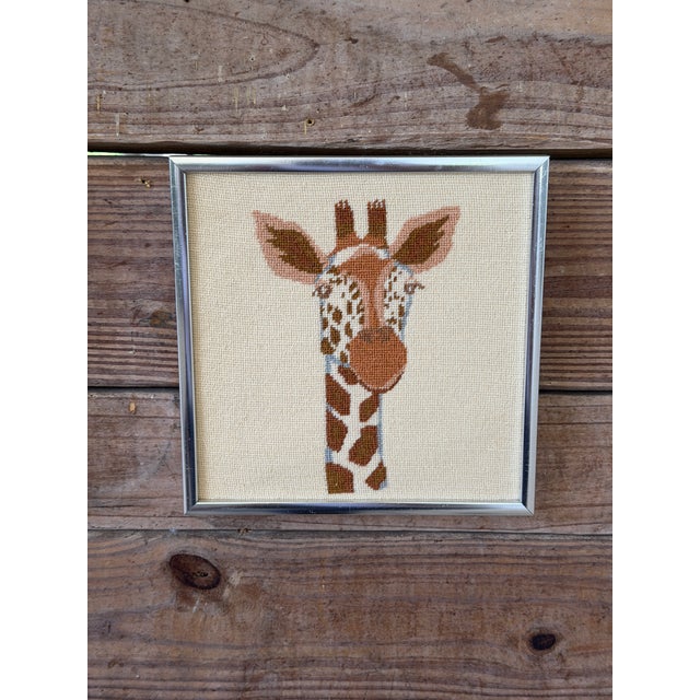 A charming pair of vintage framed needlepoint animal portraits featuring a zebra and giraffe, each beautifully hand-...