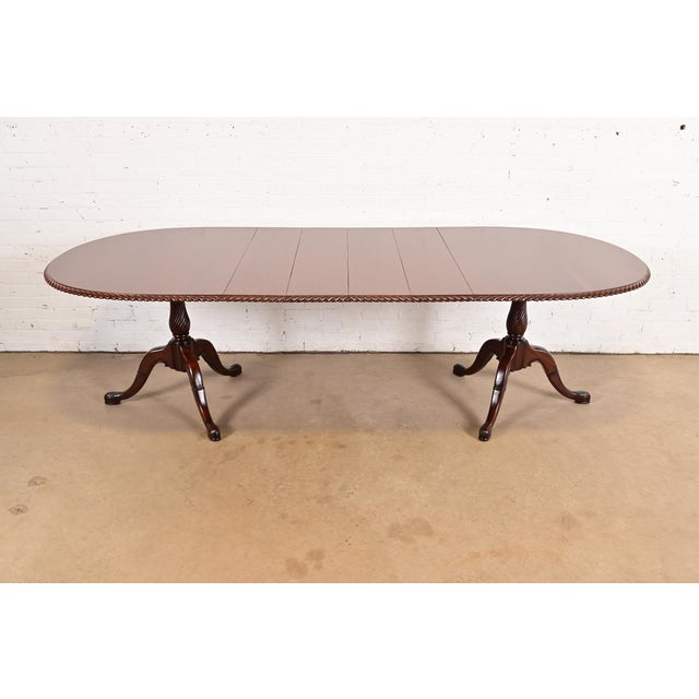 An exceptional Georgian or Chippendale style double pedestal extension dining table In the manner of Baker Furniture USA,...