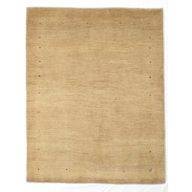 Hand-knotted Persian Lori Gabbeh rug featuring a warm, softly textured golden-beige field with delicate, scattered tribal...