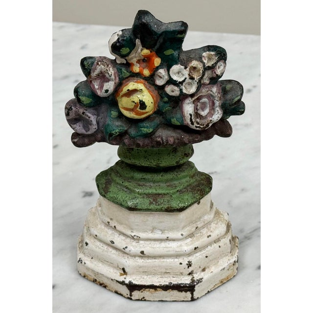 Absolutely charming antique cast iron doorstop featuring flower basket on ivory pedestal base. Vivid colors with weathered...