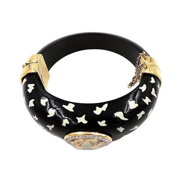 1980s Italian black Lucite cuff decorated with white spots, a faceted champagne-colored rhinestone surrounded by clear...