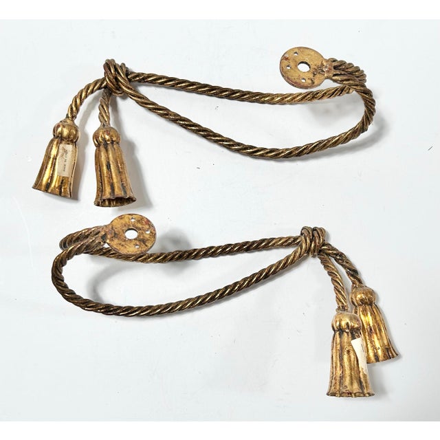 Elegant pair of vintage rope-style curtain tiebacks featuring twisted gilt cords finished with substantial decorative...