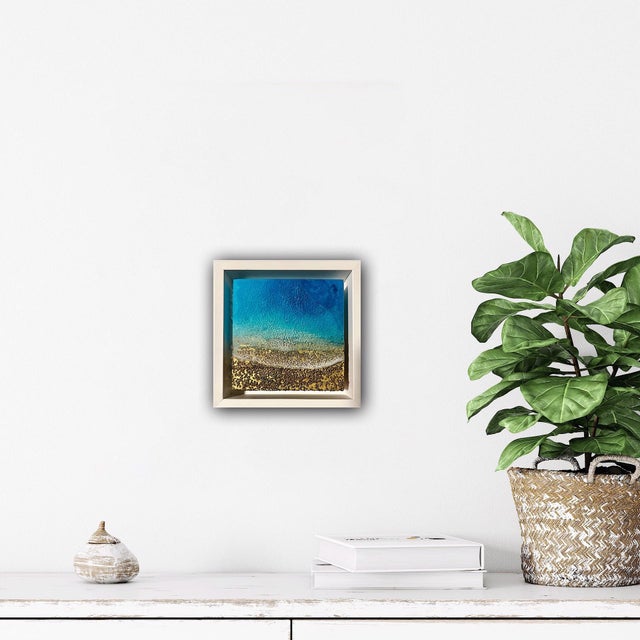 This mixed media piece captures the serene essence of the ocean, portraying a tranquil shoreline where soft waves meet...