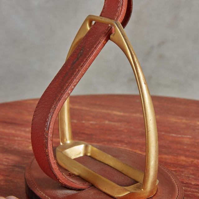 A 1950s French table lamp designed by Longchamp Paris. This lamp features a solid brass stirrup mounted and wrapped in...