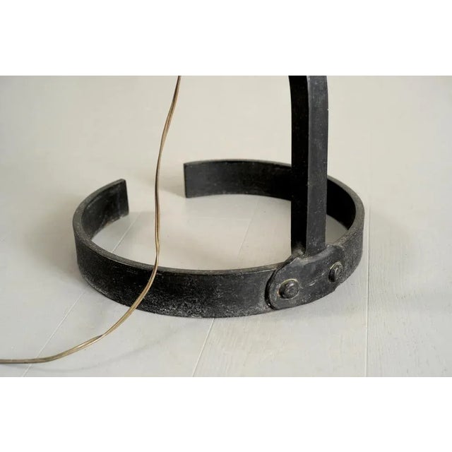 Floor lamp in blackened wrought iron signed "F.S", France 1960. The barrel is riveted to a circular flat iron base, a...