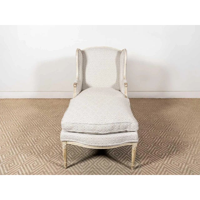 Duchesse Brisée wing back chair and ottoman with fluted legs and carved floral details. Newly upholstered. France Circa...