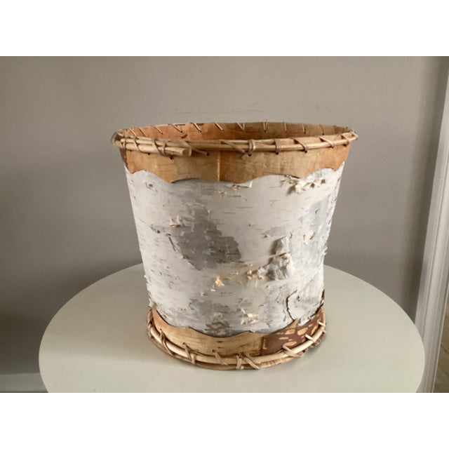 This large cylindrical shape wastebasket is made of birchbark in shades of white, gray, beige and brown. Contrasting brown...