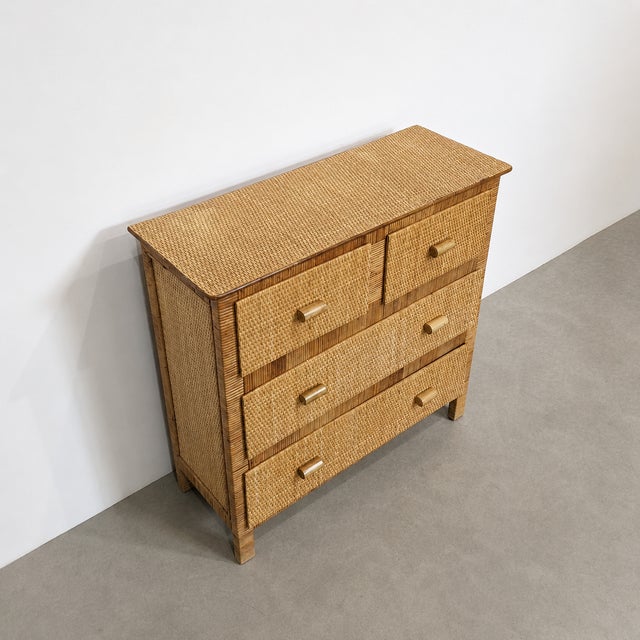 Vintage Riviera-style chest of drawers dating from the 1970s. The structure is covered in woven rattan and features four...