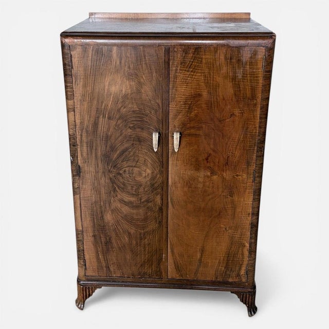A beautifully proportioned Art Deco walnut compact wardrobe, showcasing stunning figured grain across the twin doors. This...
