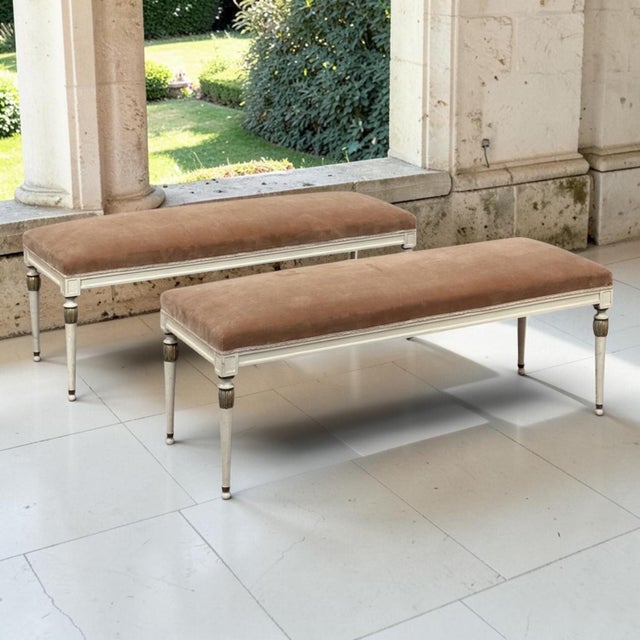 A pair of French Louis XVI painted and parcel gilt benches, graceful and refined, with their original antique white finish...