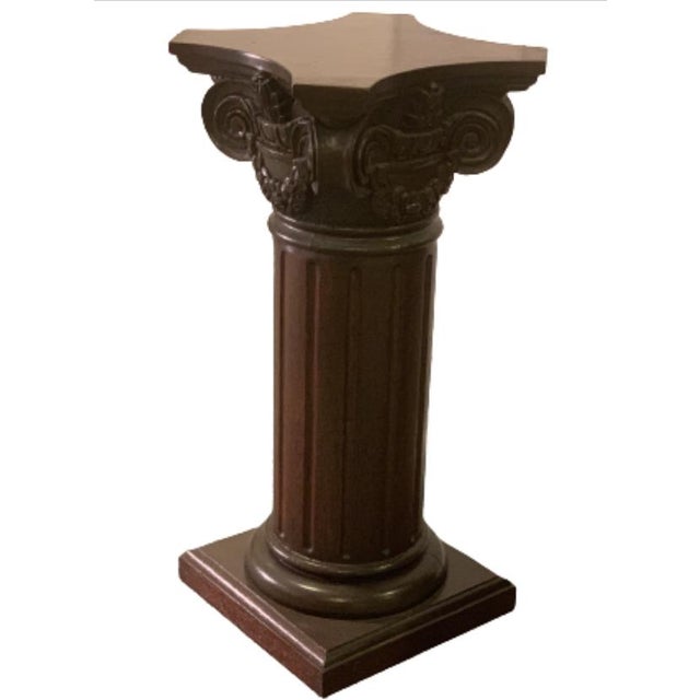 A dark stained wooden pedestal display or plant stand in the form of a classical architectural column with a fluted shaft,...