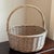 A beautifully handwoven vintage willow gathering basket featuring a generous round form and a gracefully arched wrapped...