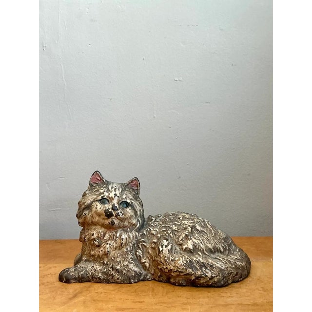 This vintage doorstop is a charming, weighty cast figure of a long-haired cat in a relaxed, reclining pose. The body is...
