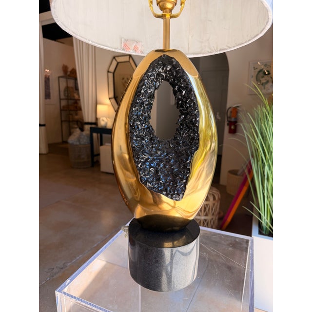 This contemporary table lamp blends modern artistry with luxurious materials for a striking statement piece. The...