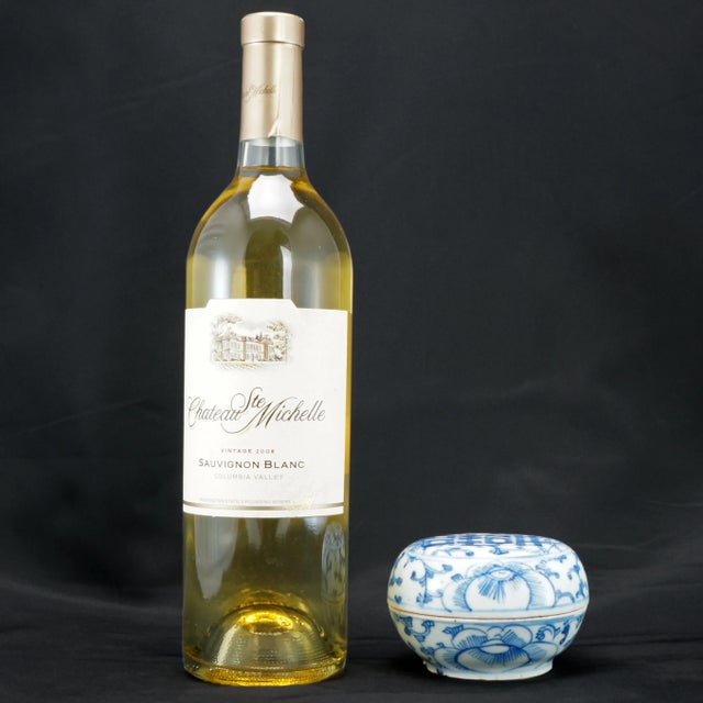 A round Chinese porcelain blue and white paste box that is decorated with delicate lotus scrolling and a Chinese double...