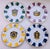 A striking set of four vintage Neiman Marcus porcelain dessert plates, each centered with a colorful, jeweled royal-crown...